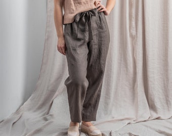 May include: Gray linen pants with a wide, tied waistband. The pants are loose-fitting and have a straight leg.