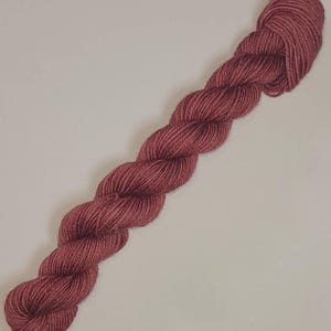 May include: A skein of deep rose colored yarn.