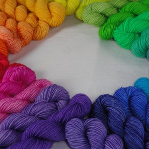 May include: A rainbow of yarn arranged in a circle, with the colors transitioning from red to orange, yellow, green, blue, and purple.