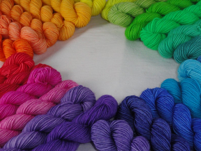 May include: A rainbow of yarn arranged in a circle, with the colors transitioning from red to orange, yellow, green, blue, and purple.