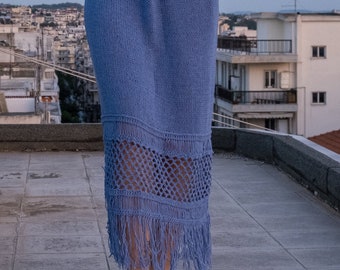 May include: A light blue knitted skirt with a crocheted lace trim and fringe. The skirt is knee-length and has a relaxed fit.