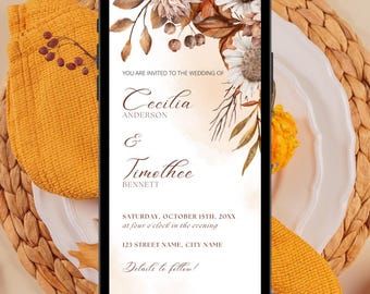 May include: A smartphone displays a wedding invitation with floral and botanical illustrations in shades of brown, white, and gold. The invitation text reads "Cecilia & Timothee" with the date and time. The phone rests on a woven placemat with a yellow napkin.