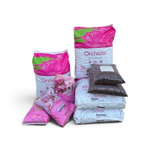 May include: A collection of Orchiata orchid bark potting medium bags in various sizes. The packaging is white and pink with orchid flower graphics and text including Orchiata, Power, and Precision. Some bags are clear plastic showing dark bark.