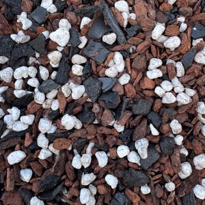 May include: Close-up of a mix of gardening materials. The image shows a blend of dark brown wood chips, black charcoal pieces, and white, rounded pebbles. The textures and colors create a natural, earthy aesthetic.