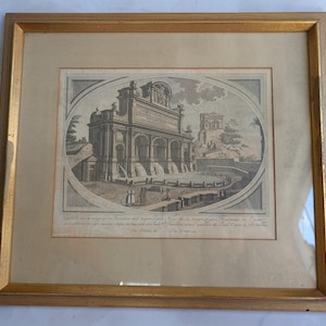 May include: Antique framed print depicting a fountain with an arched building and figures. The print is in a gold frame. The artwork is in monochrome with an oval border.