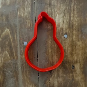 May include: Red plastic cookie cutter shaped like a pear.