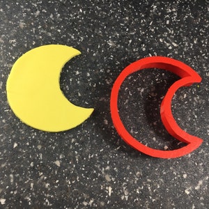 Puede incluir: Dos cortadores de galletas en forma de media luna, uno amarillo y otro rojo.