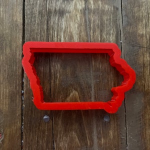 May include: A red plastic cookie cutter in the shape of the state of Iowa.