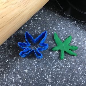 May include: Two cookie cutters in the shape of a leaf. One is blue and the other is green.