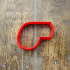 May include: A red plastic cookie cutter shaped like a whistle.