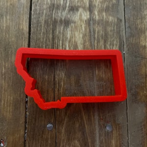 May include: Red plastic cookie cutter shaped like the state of Montana.