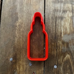 Puede incluir: Cortador de galletas de plástico rojo con forma de botella.