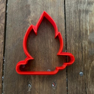 Puede incluir: Cortador de galletas de plástico rojo con forma de fogata con llamas.