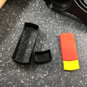 May include: Two black plastic cookie cutters shaped like a rectangle and a circle, and a red and yellow fondant cutter shaped like a rectangle.