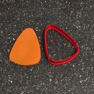May include: A red triangle-shaped cookie cutter and an orange triangle-shaped fondant cutter.