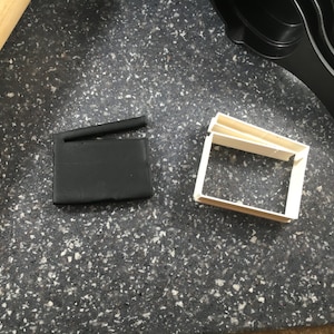 Peut inclure: Deux emportes-pièces en plastique noir, l'un en forme de clap de cinéma et l'autre en forme de rectangle.