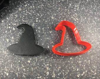 May include: Two witch hat cookie cutters, one black and one red. The cutters are made of plastic and are designed to cut out cookies in the shape of a witch's hat.