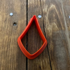 May include: A bright orange plastic cookie cutter shaped like a diamond.