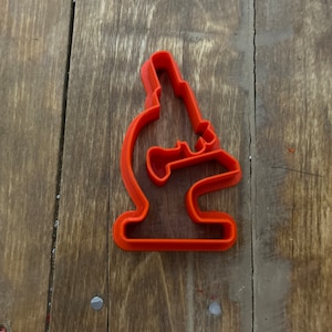 Puede incluir: Un cortador de galletas de plástico rojo con forma de microscopio.