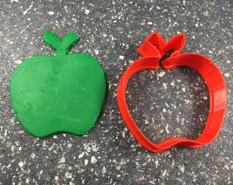 Peut inclure: Deux emportes-pièces en forme de pomme, l'un vert et l'autre rouge. L'emporte-pièce rouge est ouvert, montrant l'intérieur de l'emporte-pièce.