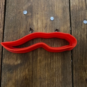 Peut inclure: Un emporte-pièce en plastique rouge en forme de moustache.