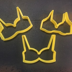 May include: Three yellow plastic cookie cutters shaped like bras.
