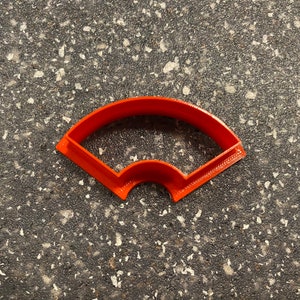 May include: Orange plastic cookie cutter shaped like a fan.