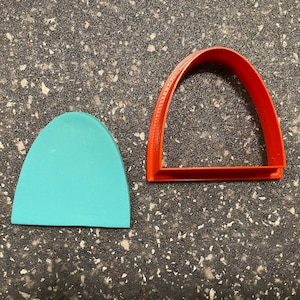 Puede incluir: Dos cortadores de galletas, uno rojo y otro azul claro, con forma de arcos.