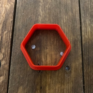Könnte beinhalten: Ein leuchtend orangefarbener, sechseckiger Ausstecher aus Kunststoff.