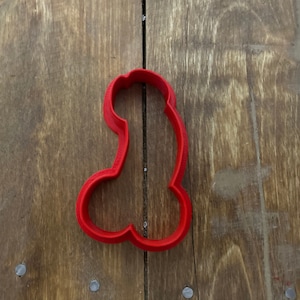 May include: Red plastic cookie cutter shaped like a human body.