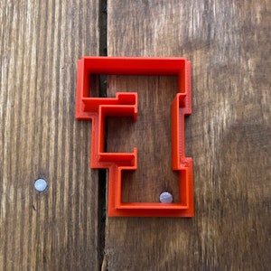 May include: A red plastic cookie cutter shaped like the letter "E".