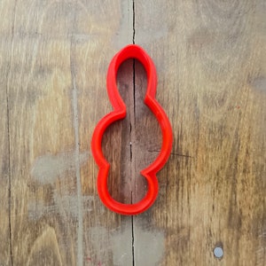Puede incluir: Un cortador de galletas de plástico rojo con forma de un ocho estilizado.