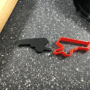May include: Two cookie cutters, one black and one red, shaped like a vintage cannon.
