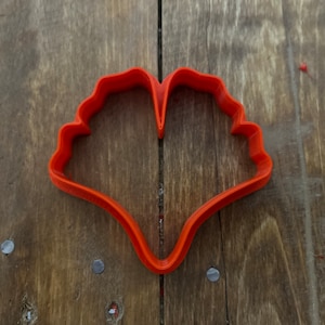 May include: Orange plastic cookie cutter shaped like a heart with a scalloped edge.