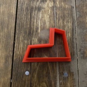 May include: A red plastic cookie cutter shaped like a lowercase letter L.