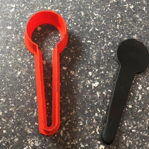 Pode incluir: Dois cortadores de biscoitos, um vermelho e outro preto, em forma de microfone.