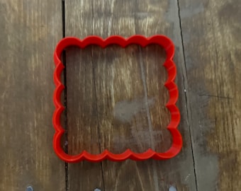 Puede incluir: Cortador de galletas de plástico rojo en forma de cuadrado con bordes festoneados.