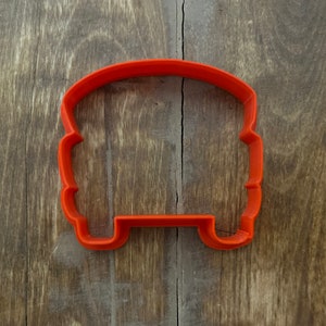 May include: Orange plastic cookie cutter shaped like a vintage camper van.