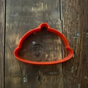 May include: Orange plastic cookie cutter shaped like a dome or cloche.