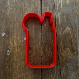 Pode incluir: Cortador de biscoitos de plástico vermelho em forma de frasco de desinfetante para as mãos.