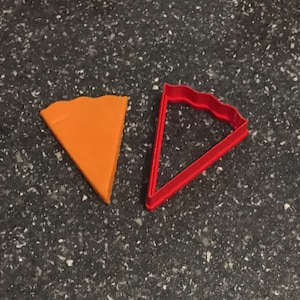 May include: Two pie crust cutters, one orange and one red, on a black speckled surface.