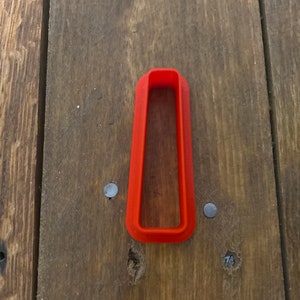 以下が含まれることがあります： 丸みを帯びた角を持つ長方形の明るいオレンジ色のプラスチック製のクッキーカッターです。