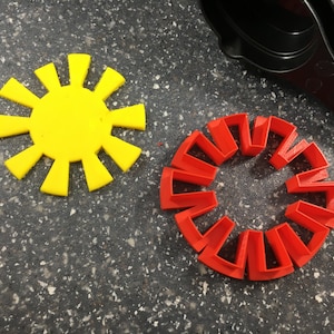 May include: Two colorful plastic shapes, one yellow sun with 12 rays and one red circle with 12 segments.
