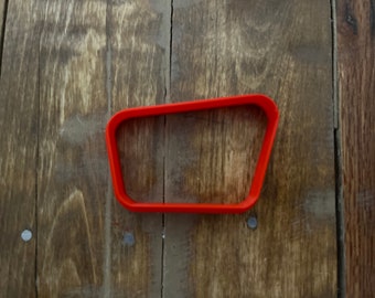 Pode incluir: Um cortador de biscoitos de plástico vermelho em forma de retângulo com cantos arredondados.