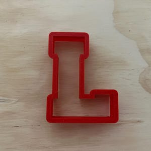 May include: Red plastic cookie cutter shaped like the letter L.