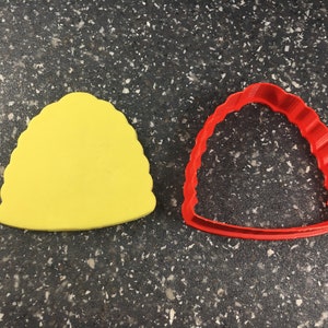 May include: A yellow plastic cookie cutter shaped like a beehive, and a red plastic cookie cutter shaped like a beehive.