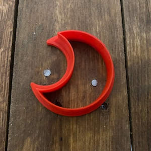 May include: A bright orange plastic crescent moon cookie cutter.