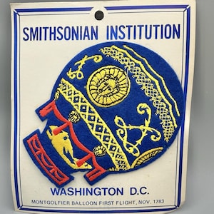 May include: A blue patch featuring a hot air balloon design with yellow and red accents. The patch includes the text "SMITHSONIAN INSTITUTION" and "WASHINGTON D.C.". The design commemorates the Montgolfier balloon's first flight in November 1783.