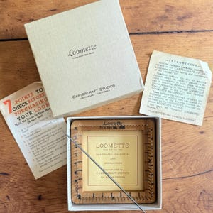 May include: A vintage Loomette weaving tool set by Cartercraft Studios, including a square wooden loom frame with metal pins, a metal needle, an instruction booklet, and a promotional insert, all housed in a beige cardboard box.