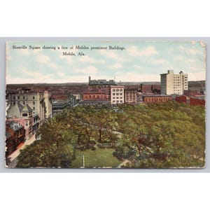 May include: A vintage postcard featuring a colorized aerial view of Bienville Square in Mobile, Alabama. The image displays a dense canopy of green trees in the foreground with various multi-story buildings in the background. Text reads: Bienville Square showing a few of Mobiles prominent Buildings, Mobile, Ala.